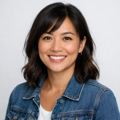 A diverse adult with casual attire and a warm smile against a light gray background.